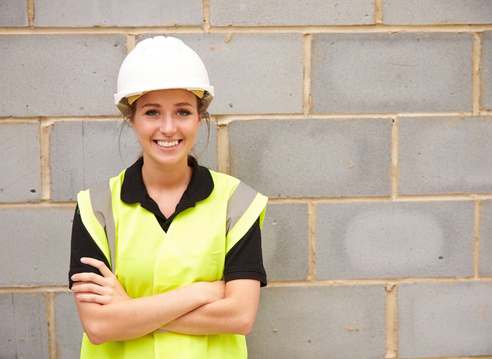 Young apprentice in a hard hat and hi-vis vest on a worksite